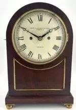 Stunning English double fusee mantle clock with arched top mahogany case, brass fish scale panel sides and stands on 4 brass bun feet