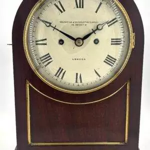 Stunning English double fusee mantle clock with arched top mahogany case, brass fish scale panel sides and stands on 4 brass bun feet