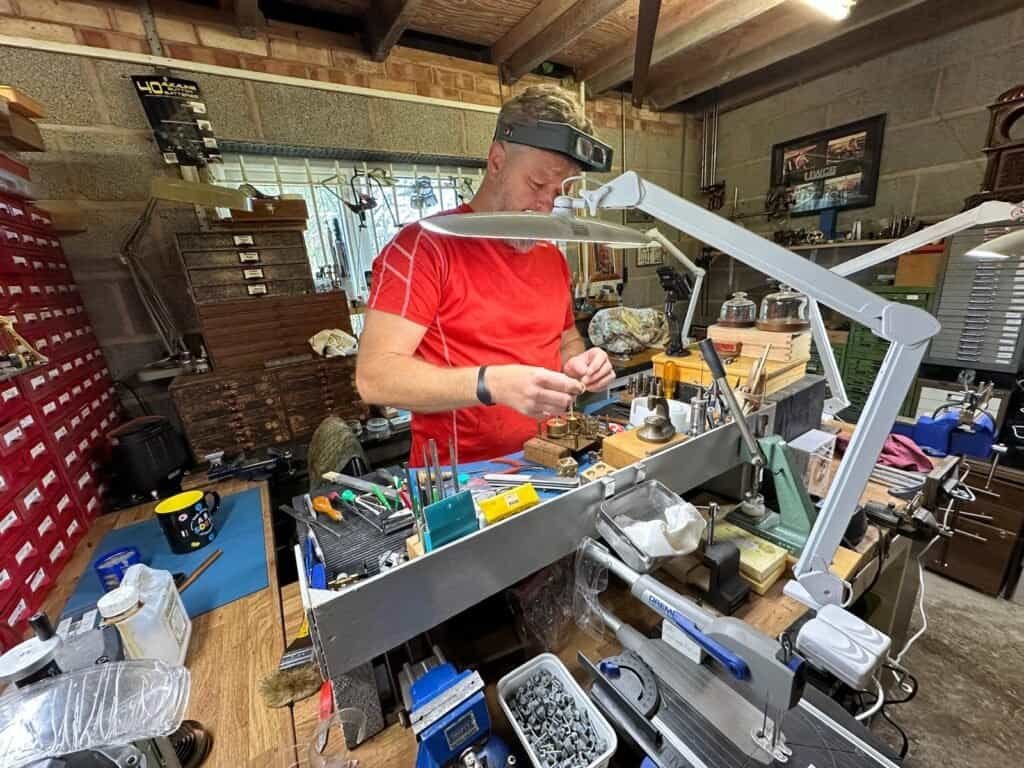 Clock repairer at the workbench in the Vintage Clocks workshop, Stonehouse
